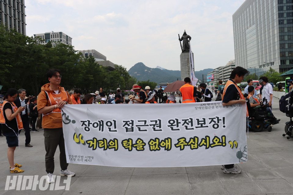 기자회견 참여자들이 “장애인 접근권 완전 보장! 거리의 턱을 없애주십시오”라고 적힌 플래카드를 들고 광화문 일대를 행진하고 있다. 사진 김소영
