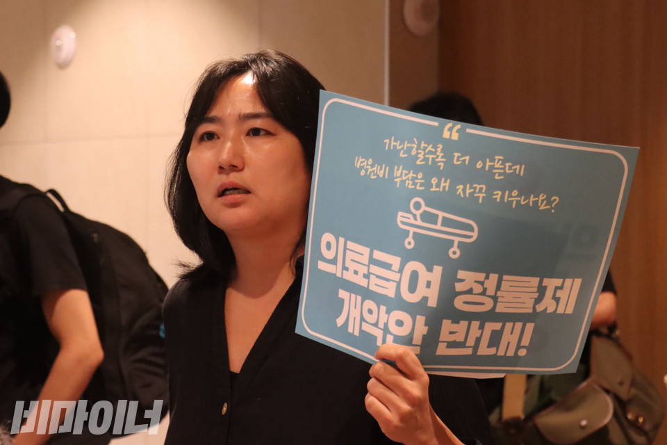 김윤영 빈곤사회연대 활동가가 울컥한 표정으로 발언하고 있다. 그의 손에는 “의료급여 정률제 개악안 반대!”라고 적힌 하늘색 피켓이 들려있다. 사진 김소영
