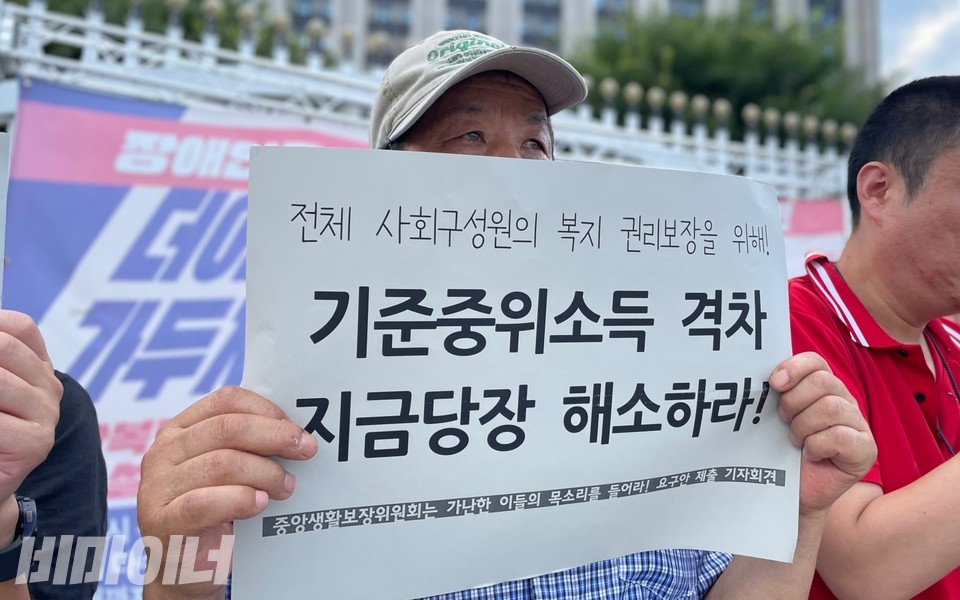 기자회견 참가자가 “전체 사회구성원의 복지 권리보장을 위해 기준중위소득 격차 지금 당장 해소하라”라고 적힌 피켓을 들고 있다. 사진 하민지