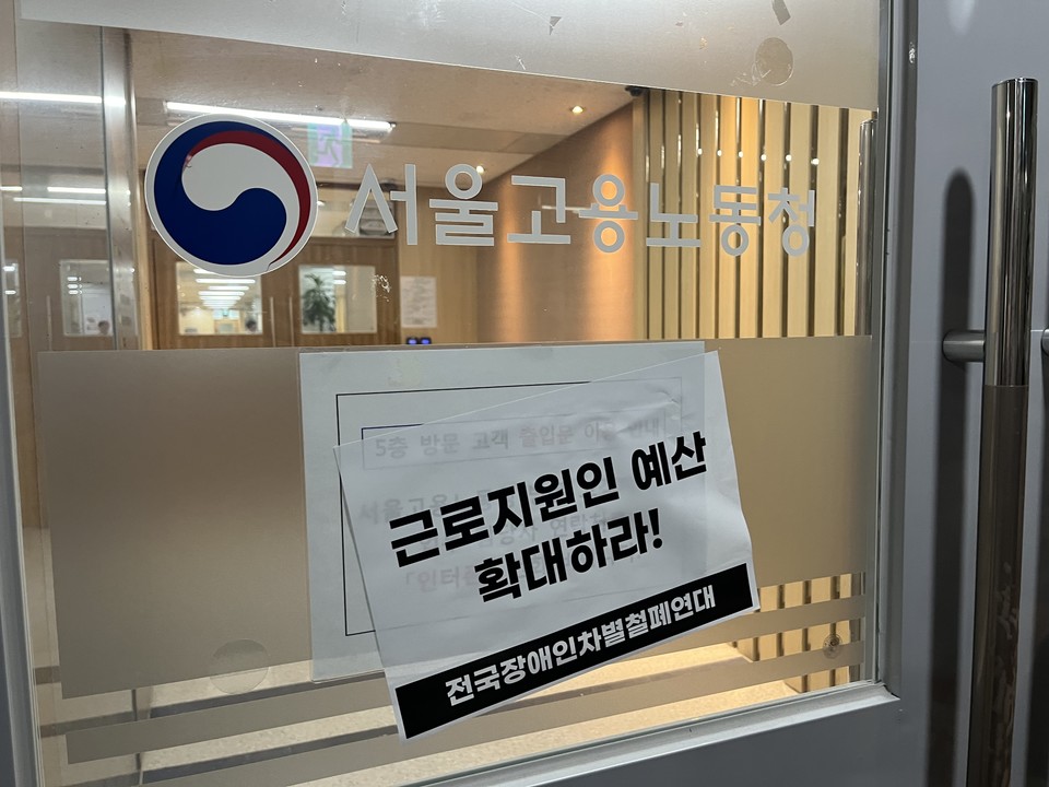 서울지방고용노동청 출입구에 전장연 활동가들이 붙인 "근로지원인 예산 보장하라" 스티커가 붙혀져있다. 사진 전국장애인차별철폐연대