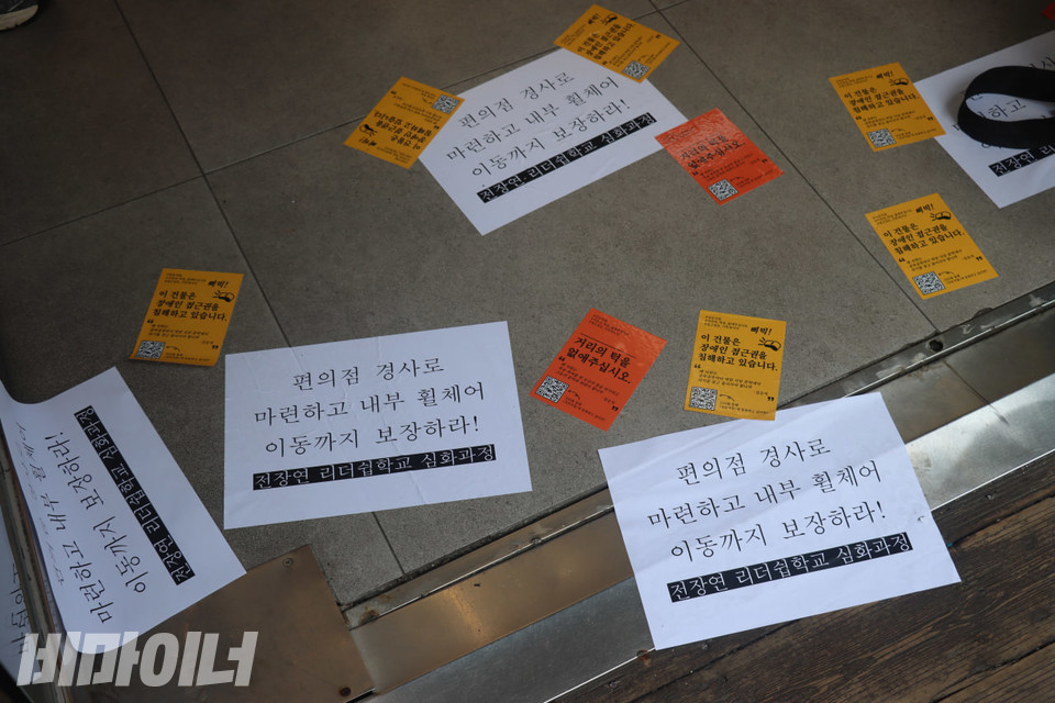 활동가들이 CU편의점 마로니에공원점 입구 바닥에 붙인 ‘권리스티커’들.  “편의점 경사로 마련하고 내부 휠체어 이동까지 보장하라!”고 적혀있다. 사진 김소영