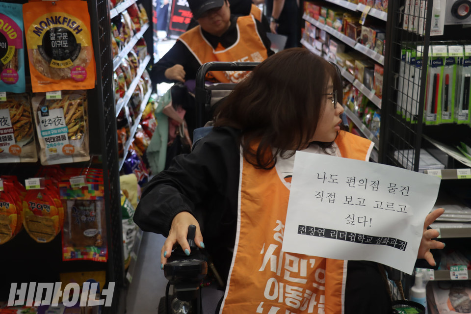 황순원 전남장애인차별철폐연대 활동가가 편의점 내부를 둘러보고 있다. 그의 손에는 “나도 편의점 물건 직접 보고 고르고 싶다!”라고 적힌 종이 피켓이 들려있다. 사진 김소영