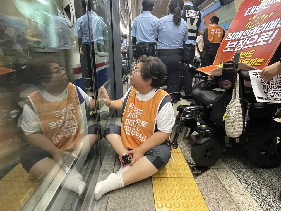 이형숙 전장연 상임공동대표가 휠체어에서 낙상한 채 스크린도어를 바라보고 있다. 사진 전장연