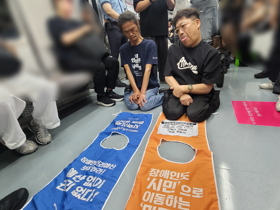 전국장애인차별철폐연대 활동가들이 지하철 바닥을 기며 장애인권리예산 보장을 시민들에게 호소하고 있다. 사진 전국장애인차별철폐연대