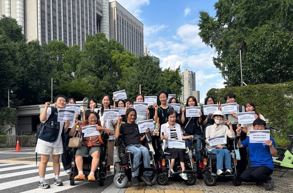 최윤정 씨와 변호인단이 법원 앞에서 손피켓을 들고 있다. 사진 전국장애노인연대