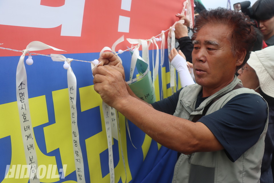 한 기자회견 참가자가 퍼포먼스의 일환으로 국가폭력 피해자들의 요구가 담긴 리본을 줄에 묶고 있다. 사진 김소영