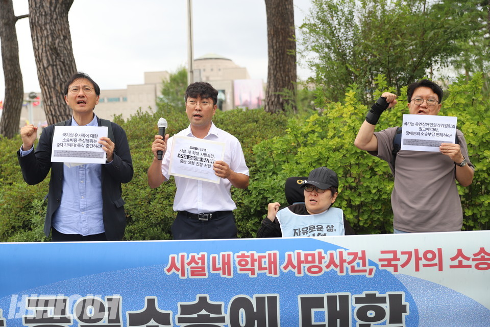 기자회견 참가자들이 주먹 쥔 손을 높이 들며 구호를 외치고 있다. 사진 김소영