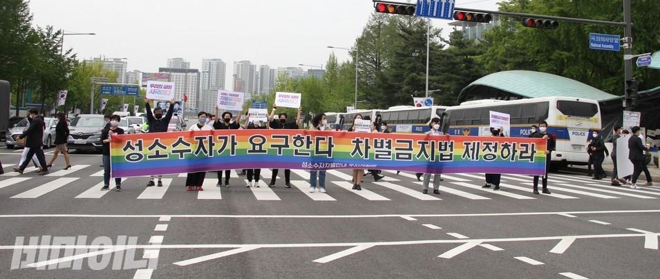 무지개색 바탕에 ‘성소수자가 요구한다. 차별금지법 제정하라’라고 쓰여진 플랜카드. 사진 비마이너