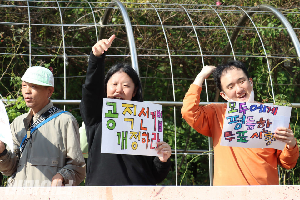 지난해 10월 10일, 발달장애인들이 투표보조를 제공하지 않은 국가를 상대로 제기한 차별구제청구소송에서 1심 승소 후 서울중앙지방법원에서 기자회견을 열었다. 기자회견 참여자들이 손을 번쩍 들며 구호를 외치고 있다. 그들의 손에는 “공직선거법 개정하라”, “모두에게 평등한 투표 시행”이라고 알록달록 적힌 종이 피켓이 들려있다. 사진 김소영