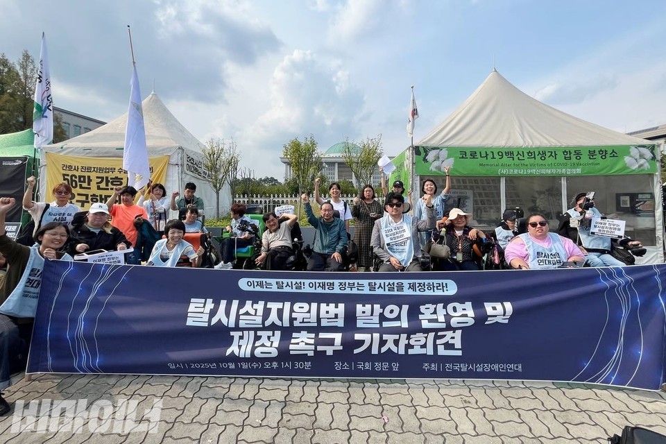 국회 앞에서 기념사진을 찍는 기자회견 참여자들. 주먹 쥔 손을 높이 들고 구호를 외치고 있다. 사진 김소영