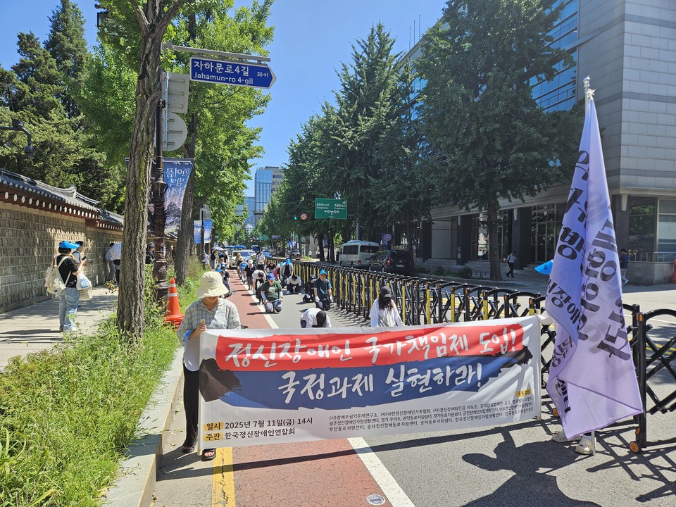 지난 7월 11일 한국정신장애인연합회 회원들이 국정기획위원회 인근에서 ‘정신장애인 국가책임제 도입 국정과제 실현하라’라고 적힌 현수막을 들고 삼보일배 행진을 하고 있다. 사진 한국정신장애인연합회