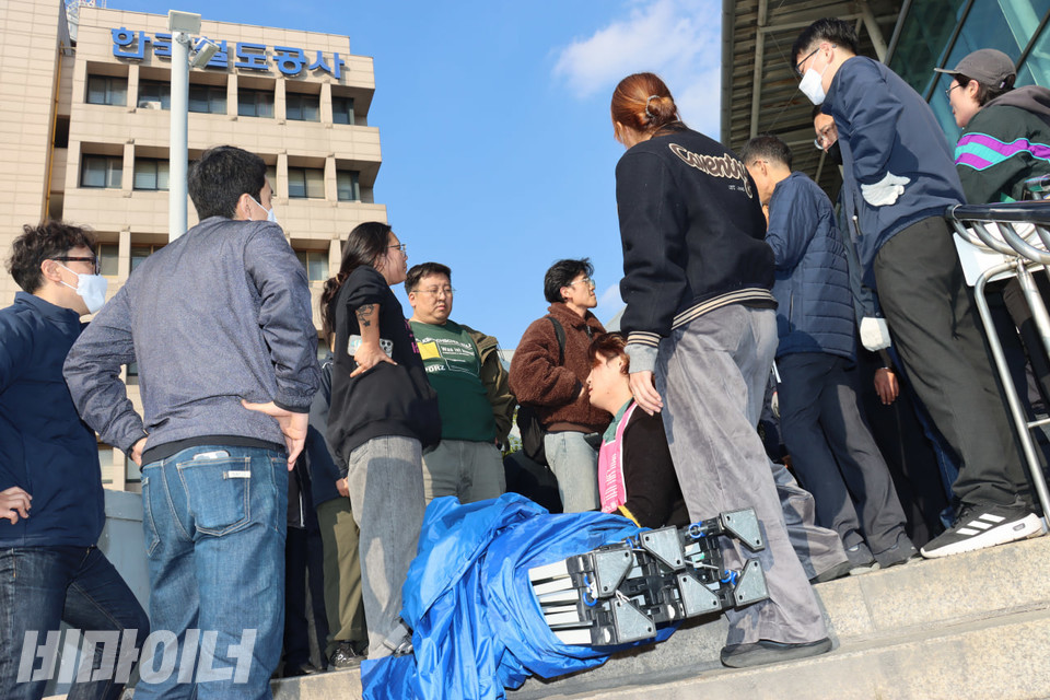 밖으로 천막을 빼낸 코레일 직원들과 전장연 활동가들이 대치하고 있다. 그들의 앞에 천막이 놓여있다. 사진 김소영