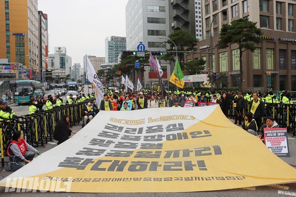 장애인 노동자 대회 참가자들이 행진하면서 커다란 현수막을 펼쳤다. 현수막에는 “이것도 노동이다, 권리중심 중증장애인 맞춤형 공공일자리 확대하라”라고 적혀 있다. 사진 하민지
