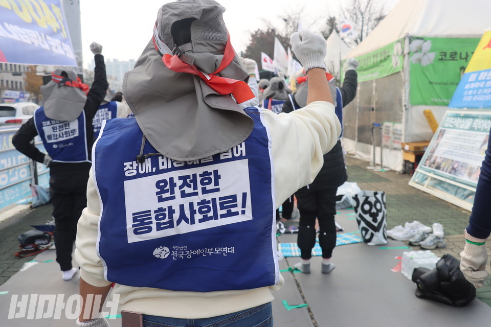 오체투지 참여자의 뒷모습. 그는 “장애, 비장애를 넘어 완전한 통합사회로!”라고 적힌 파란색 몸피씨(조끼)를 입고 있다. 사진 김소영