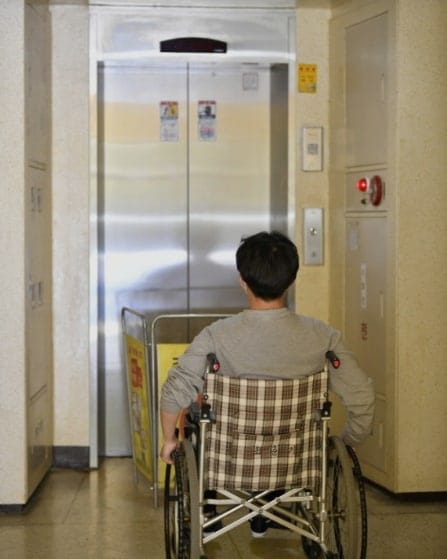 2022년 김포의 한 아파트에서도 엘레베이터 공사로 휠체어 이용자의 이동권이 제한되는 일이 있었다. 사진 속에는 엘레베이터 앞 공사 중이라고 표지가 설치되어 있고 휠체어 이용자가 그 앞에 가만히 있다. 사진 김포장애인자립생활센터 페이스북