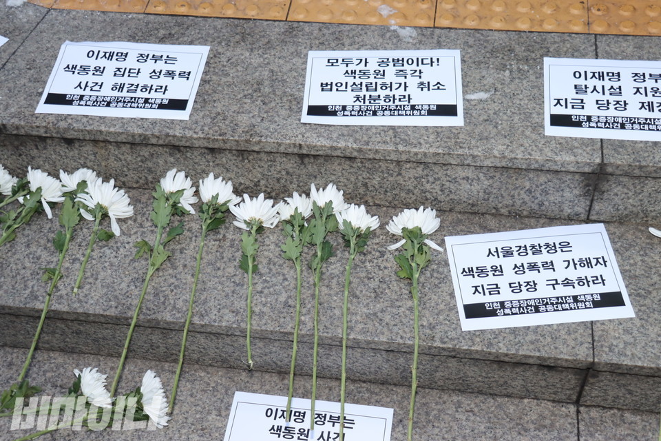 서울경찰청 앞 계단에 놓인 국화꽃과 종이 피켓들. 피켓에는 “서울경찰청은 색동원 성폭력 가해자 지금 당장 구속하라”등이 적혀있다. 사진 김소영