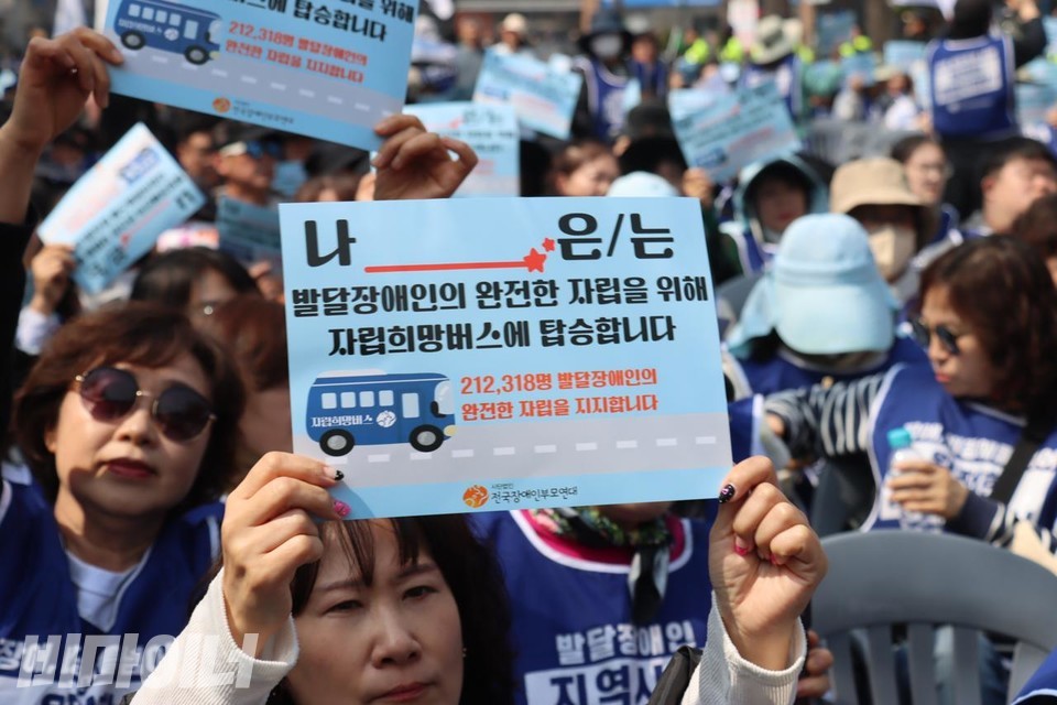 전국장애인부모연대 회원들이 ‘나는 발달장애인의 완전한 자립을 위해 자립희망버스에 탑승합니다’라고 적힌 선전물을 들고 있다. 사진 이재민