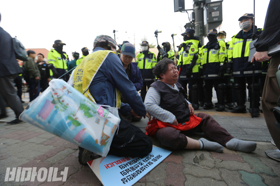 오후 5시 58분, 이 회장이 고통스러운 표정을 지으며 인도 바닥에 앉아 있다. 신발과 안경이 모두 벗겨진 이 회장을 경찰들이 둘러싸고 있다. 사진 김소영