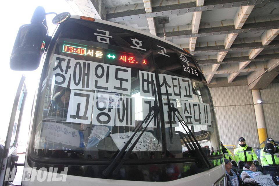 장애인들이 버스를 막고 "장애인도 버스타고 고향에 가고 싶다!"를 한 글자씩 출력해 버스 앞면 유리에 붙였다. 사진 비마이너 DB
