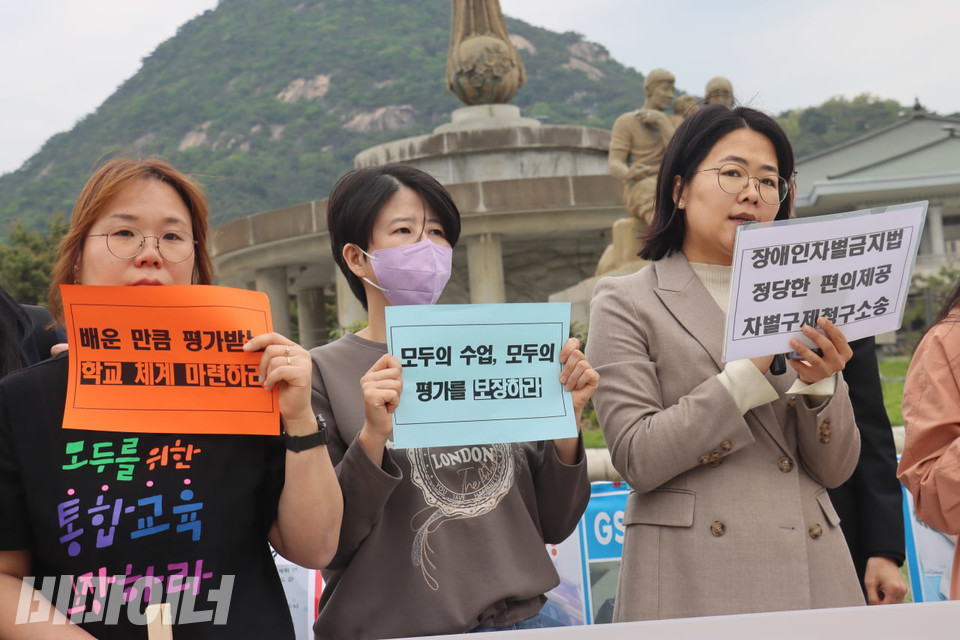 이수연 법조공익모임 나우 변호사가 발언하고 있다. 그의 옆에는 기자회견 참가자들이 “배운 만큼 평가 받는 학교 체계 마련하라”,  모두의 수업, 모두의 평가를 보장하라” 등이 적힌 손피켓을 들고 있다. 사진 김소영