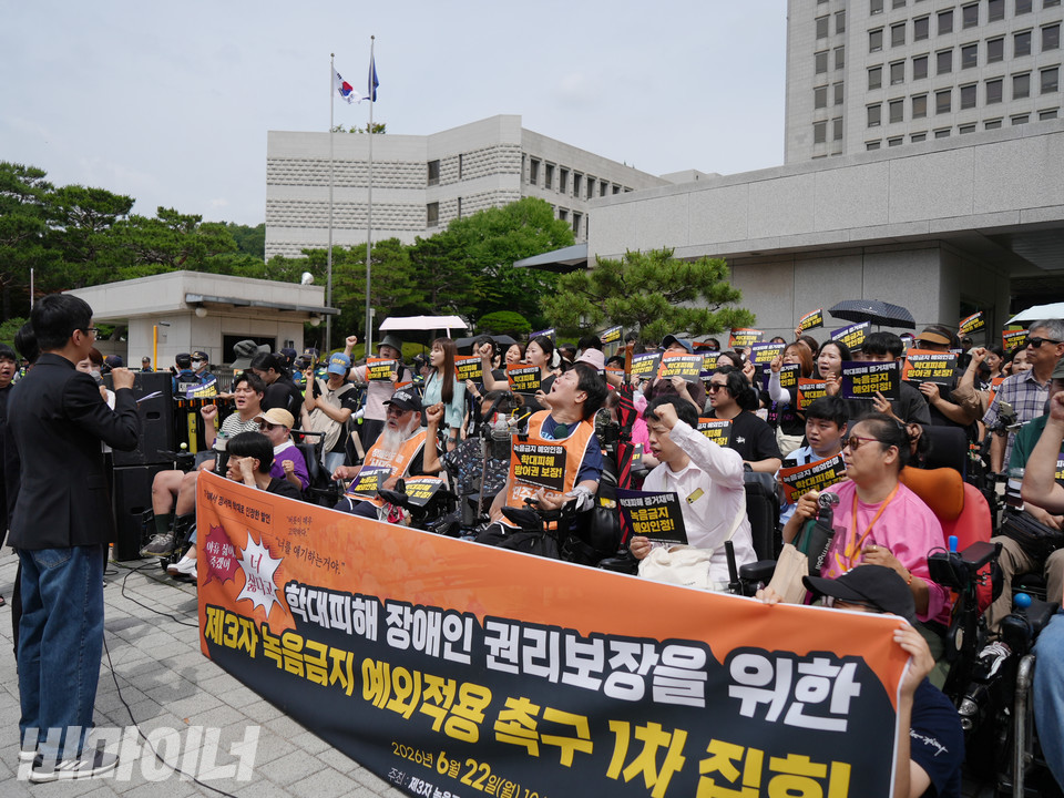 대법원 앞에서 열린 기자회견에서 참가자들이 제3자 녹음 예외 인정을 촉구하며 손피켓을 들고 구호를 외치고 있다. 현수막에는 ‘학대피해 장애인 권리보장을 위한 제3자 녹음금지 예외적용 촉구’라고 적혀 있다. 사진 장호경