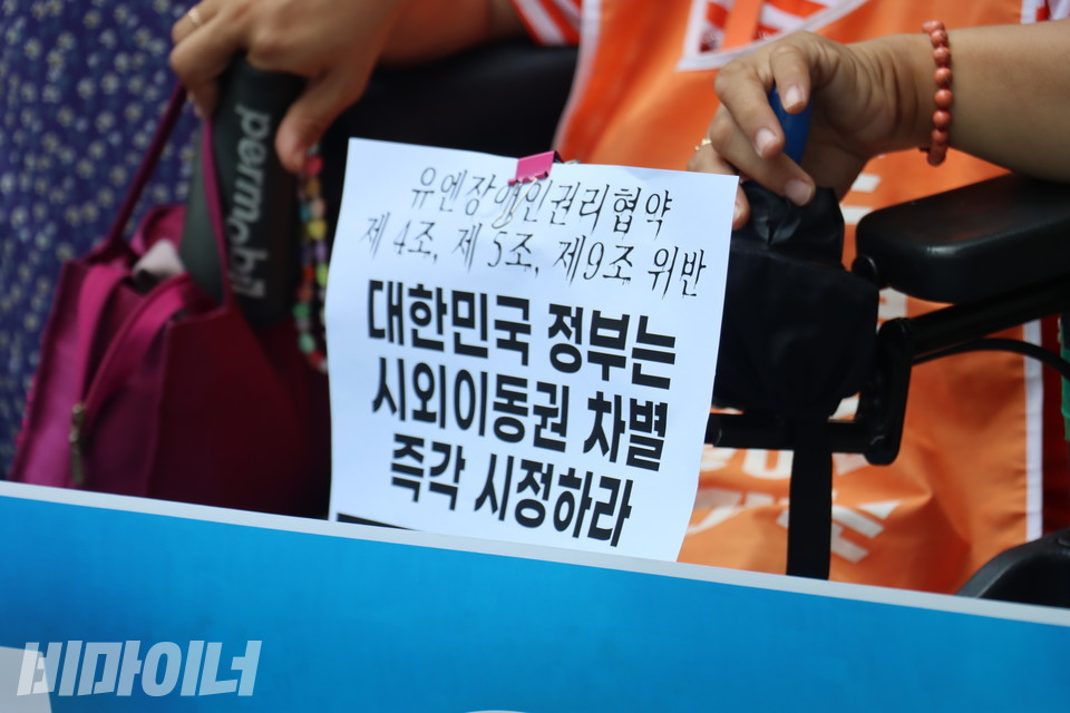 휠체어 이용 참가자가 휠체어에 붙인 손피켓. "유엔장애인권리협약 제4조, 제5조, 제9조 위반. 대한민국 정부는 시외이동권 차별 즉각 시정하라"가 적혀 있다. 사진 이재민