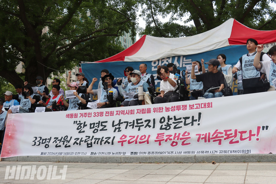 보고대회 참가자들이 주먹 쥔 손을 높이 들고 구호를 외치고 있다. 그들의 앞에는 “한 명도 남겨두지 않는다! 33명 전원 자립까지 우리의 투쟁은 계속된다!”라고 적힌 현수막이 있다. 사진 김소영