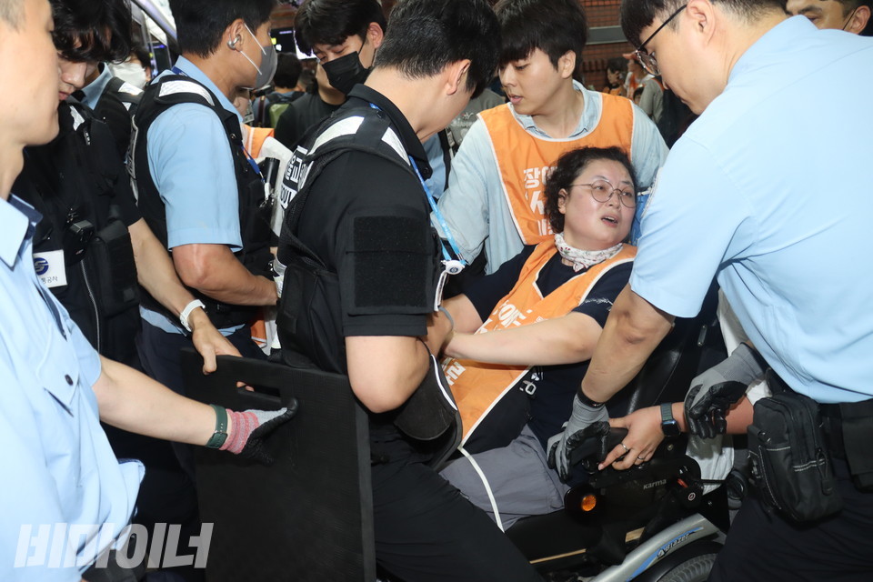 서울교통공사 보안관과 경찰들이 당사자의 동의 없이 전동휠체어를 만지며 지하철 탑승을 저지하고 있다. 방패를 들고 있는 공사 보안관의 모습도 보인다. 사진 김소영