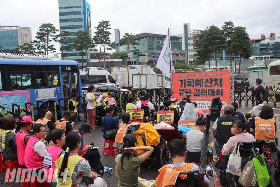 한국재정정보원 앞에 전국장애인야학협의회 활동가들과 야학 학생들이 모여 결의대회를 진행하고 있다. 무대 앞 대형 현수막에는 “기획예산처 규탄 결의대회”가 적혀 있다. 사진 이재민