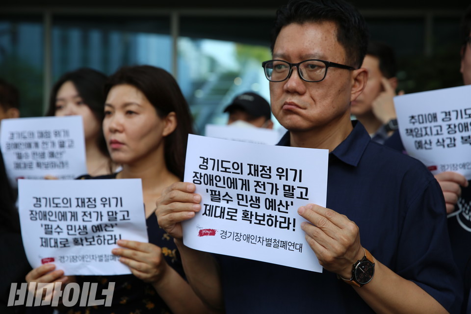 기자회견 참가자가 “경기도의 재정 위기 장애인에게 전가 말고 ‘필수 민생 예산’ 제대로 확보하라”라고 적힌 손피켓을 들고 있다. 사진 김소영