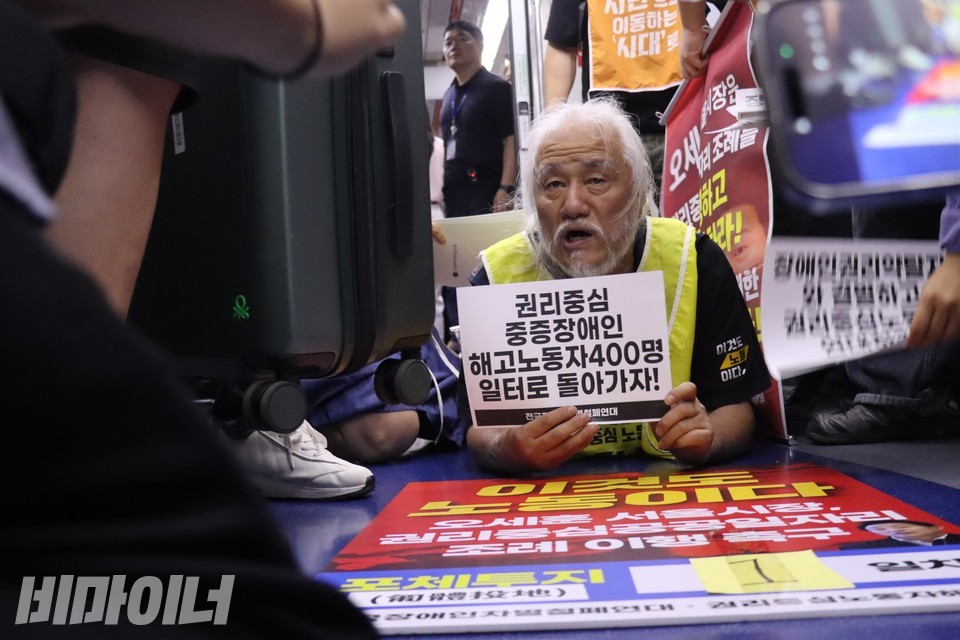 28일 오전, 박경석 전장연 상임공동대표가 손에 “권리중심 중증장애인 해고노동자 400명 일터로 돌아가자!”라고 적힌 손피켓을 들고 출근길 지하철 바닥을 기고 있다. 사진 김소영
