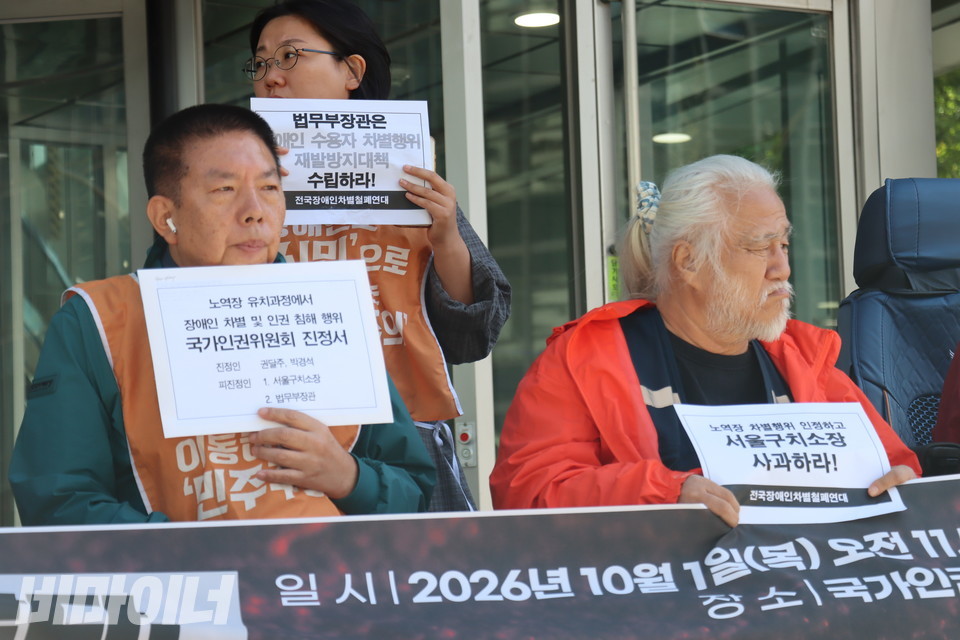 법무부장관과 서울구치소장을 진정한 권달주・박경석 전국장애인차별철폐연대 상임공동대표. 권 대표 손에는 "노역장 유치과정에서 장애인 차별 및 인권침해 행위 국가인권위원회 진정서"가 적힌 봉투가 들려 있다. 박 대표도 "노역장 차별행위 인정하고 서울구치소장 사과하라!"가 적힌 피켓을 들었다. 사진 이재민