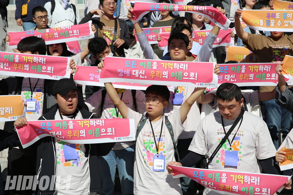 “모든 이름을 기억하라! 장애 대신, 우리의 이름으로!”라고 적힌 손피켓을 들고 있는 한국피플퍼스트대회 참가자들. 사진 김소영